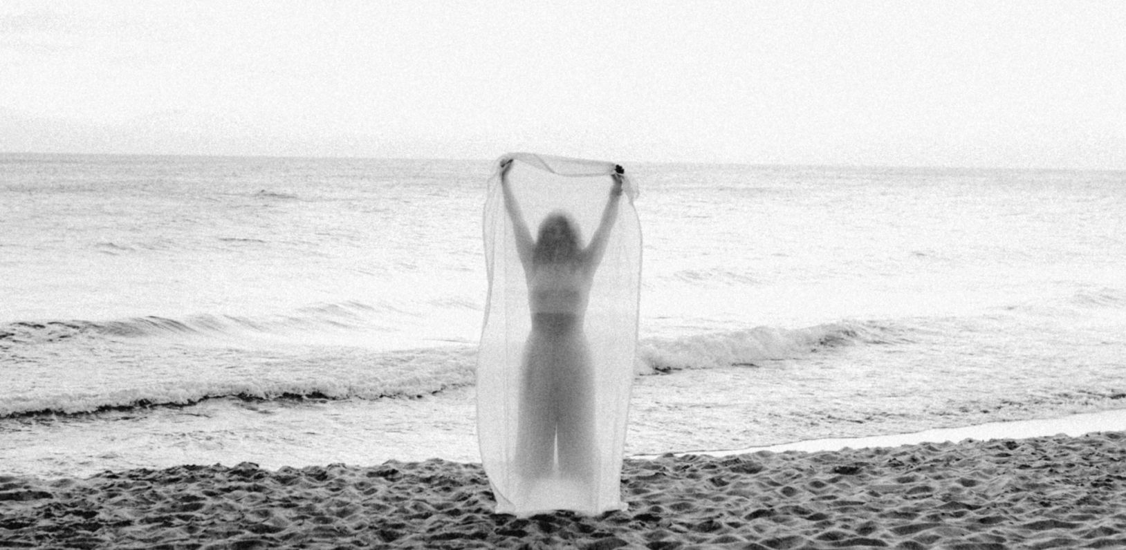 Mujer en la orilla del mar con los brazos abiertos